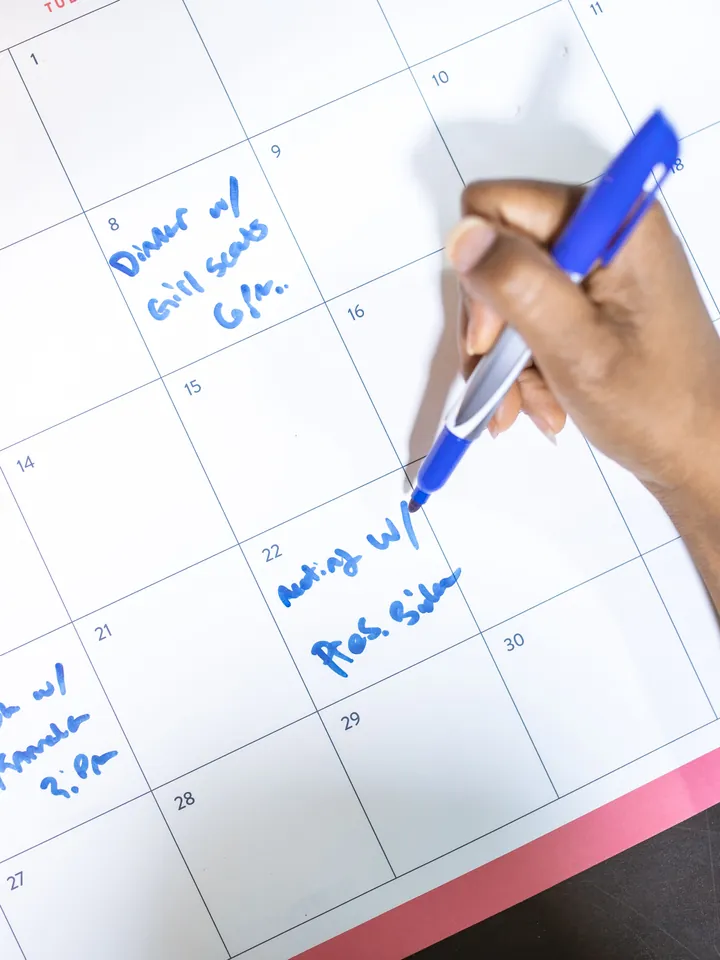 Mână scriind într-un calendar